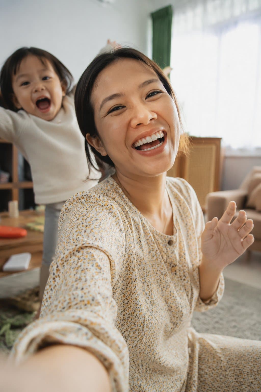 Mum filming a piece to camera while her toddler photobombs