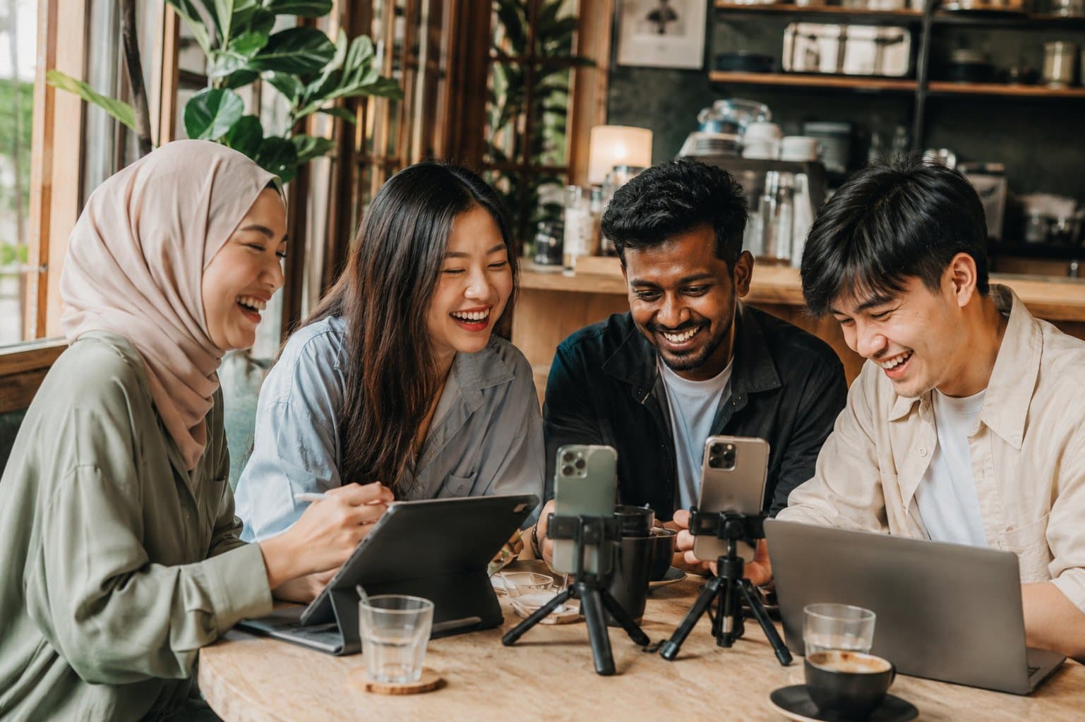 Four creators laughing around a cafe table